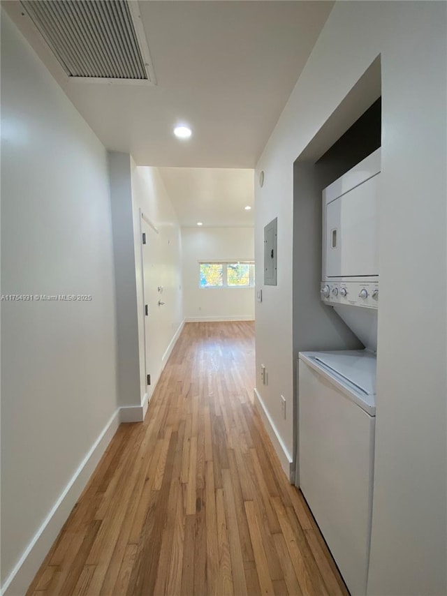 hall with baseboards, light wood-style floors, visible vents, and stacked washer / drying machine