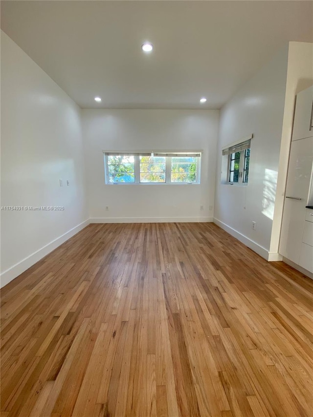 spare room featuring light wood finished floors, baseboards, and recessed lighting