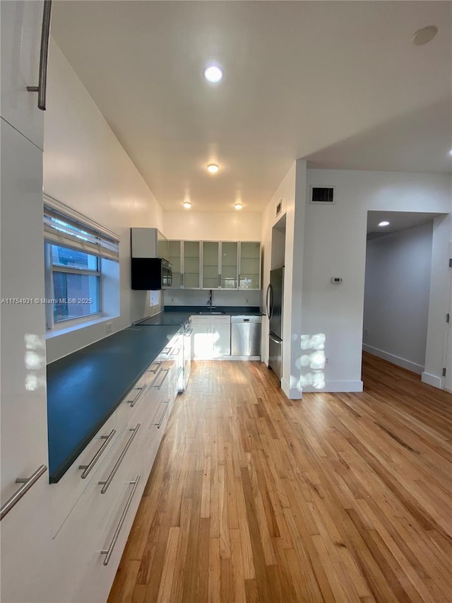 kitchen featuring visible vents, baseboards, light wood-style flooring, glass insert cabinets, and appliances with stainless steel finishes