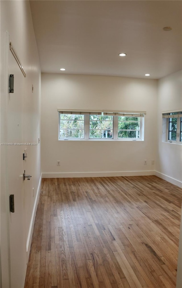 empty room with recessed lighting, wood-type flooring, and baseboards