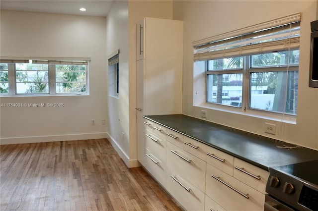 kitchen with dark countertops, recessed lighting, light wood-style floors, modern cabinets, and baseboards