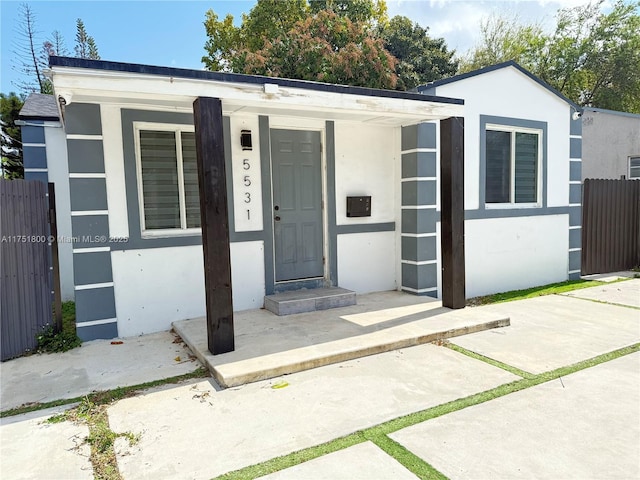 view of front of home featuring covered porch, fence, and stucco siding