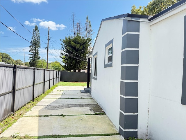 view of side of property featuring a patio area, fence, and stucco siding