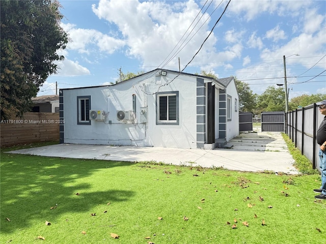 back of house featuring a lawn, a patio area, fence, and stucco siding