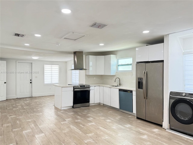 kitchen with stainless steel appliances, a sink, visible vents, wall chimney exhaust hood, and washer / dryer