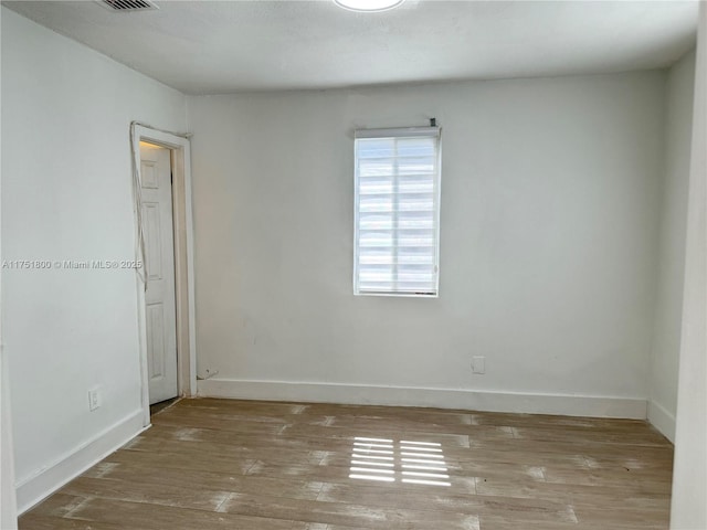 unfurnished room with hardwood / wood-style floors, visible vents, and baseboards