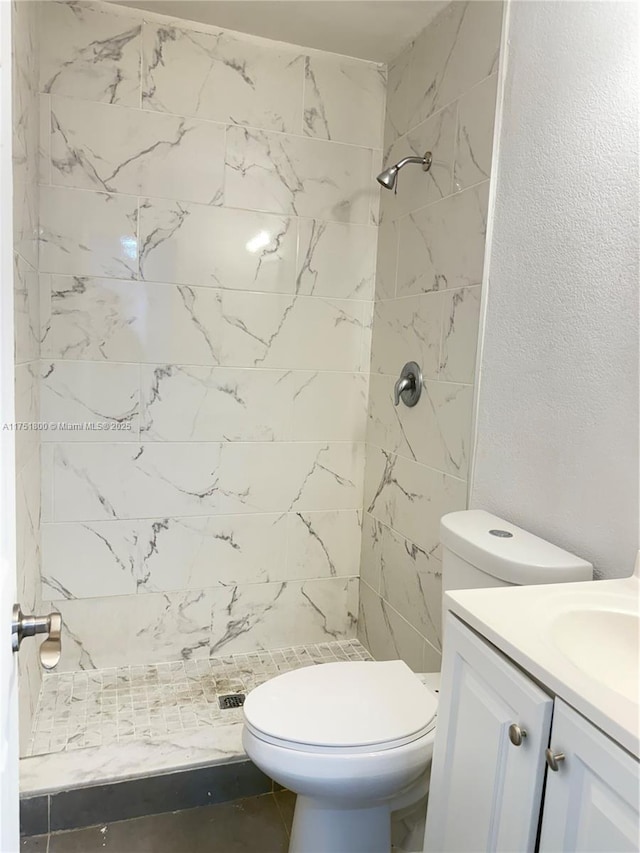 bathroom with toilet, a stall shower, a textured wall, and vanity