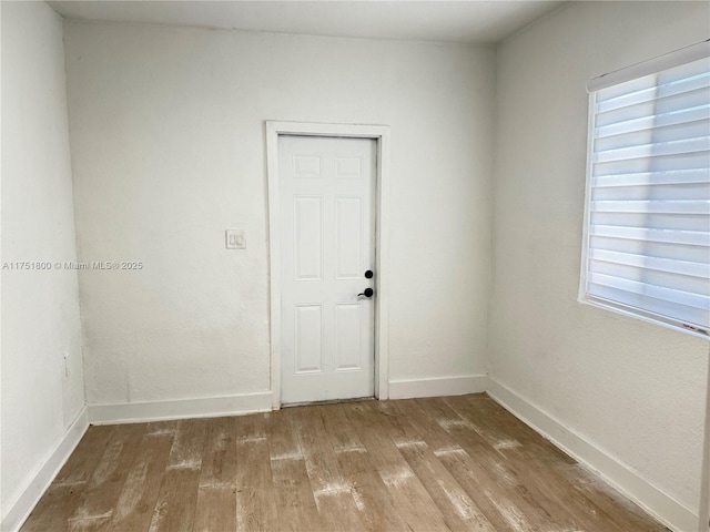 empty room featuring wood finished floors, a wealth of natural light, and baseboards