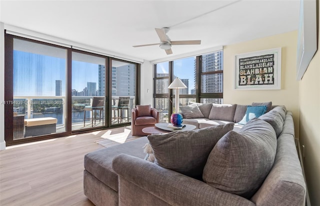 living area featuring expansive windows, a view of city, ceiling fan, and wood finished floors