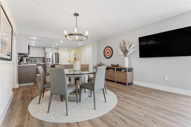 dining area with a chandelier, recessed lighting, baseboards, and light wood finished floors