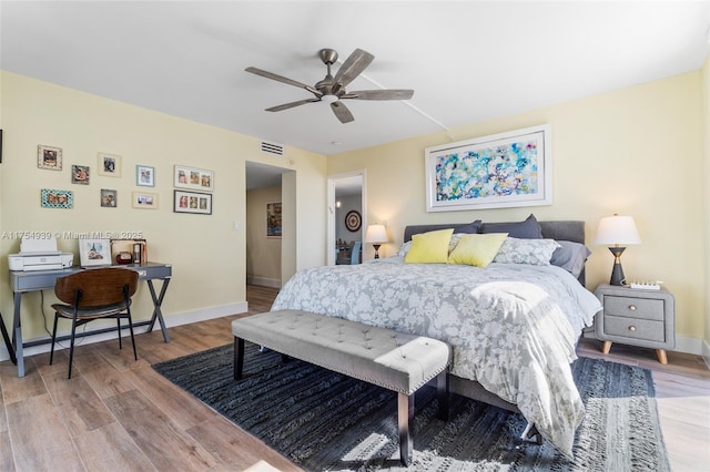 bedroom featuring light wood-type flooring, baseboards, visible vents, and a ceiling fan