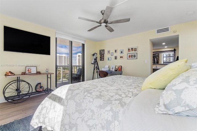 bedroom featuring visible vents, a ceiling fan, wood finished floors, access to exterior, and expansive windows