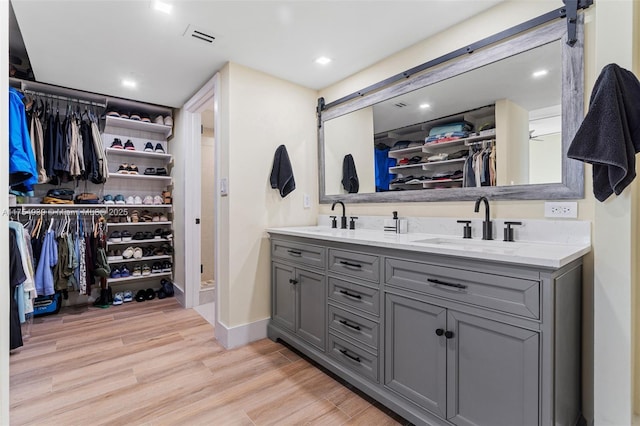 full bath with double vanity, wood finished floors, a spacious closet, and a sink