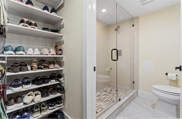 bathroom featuring toilet, a stall shower, visible vents, and baseboards