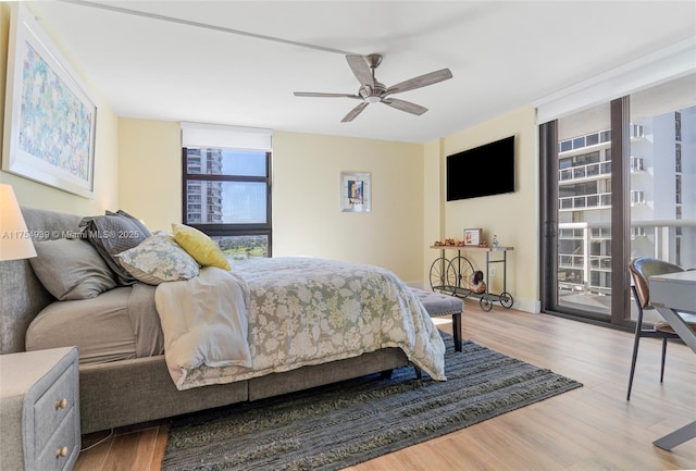 bedroom with expansive windows, access to outside, and wood finished floors