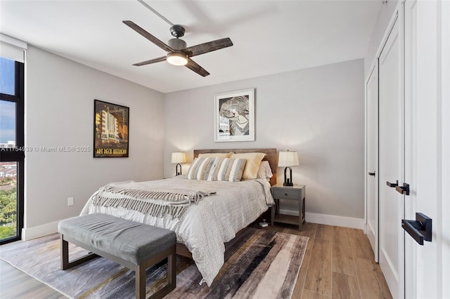 bedroom with a ceiling fan, baseboards, and wood finished floors