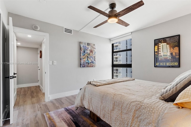 bedroom with ceiling fan, light wood-style flooring, visible vents, and baseboards