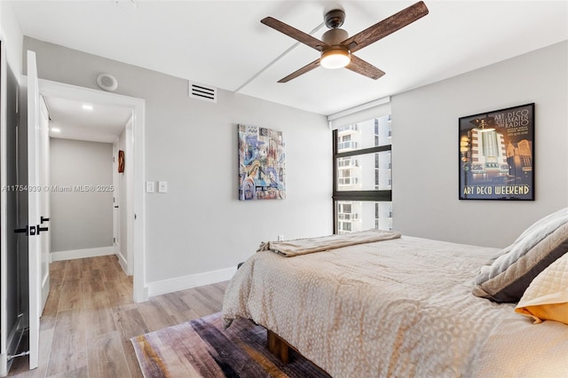 bedroom with light wood-style floors, visible vents, ceiling fan, and baseboards