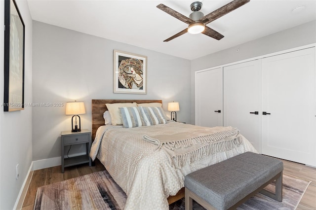 bedroom featuring a closet, wood finished floors, a ceiling fan, and baseboards