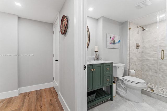 bathroom featuring wood finished floors, a shower stall, toilet, and baseboards