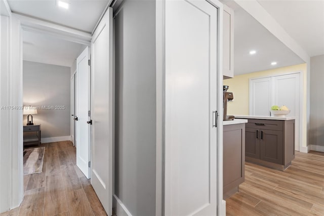 corridor featuring light wood-type flooring, baseboards, and recessed lighting