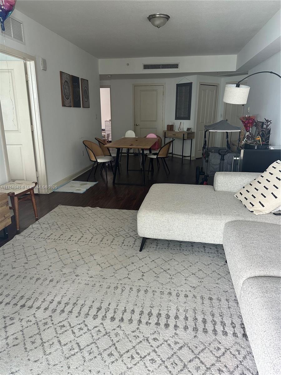 living room featuring visible vents, baseboards, and wood finished floors