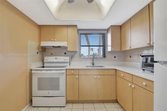 kitchen featuring a tray ceiling, light countertops, electric range, a sink, and under cabinet range hood