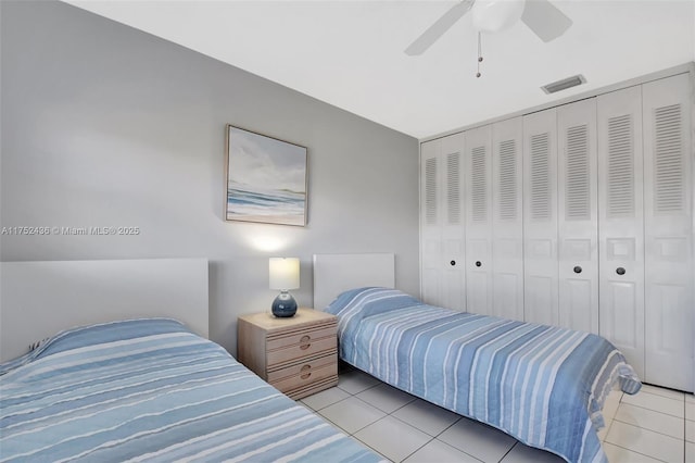 tiled bedroom with a closet, visible vents, and ceiling fan