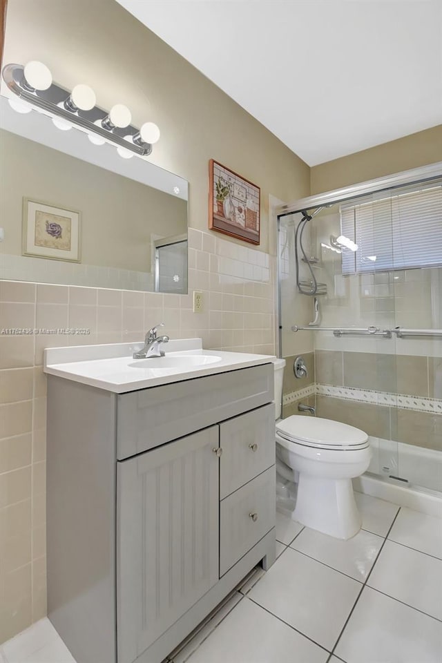 bathroom with toilet, a shower stall, tile walls, and vanity