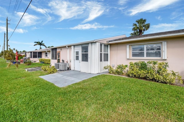 back of property with central air condition unit, a yard, a patio, and stucco siding