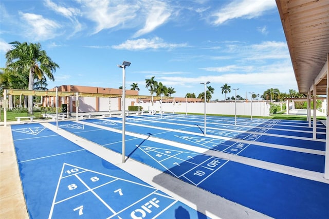 view of community with shuffleboard and fence