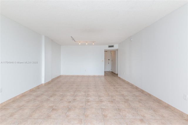 spare room with visible vents, a textured ceiling, baseboards, and light tile patterned floors