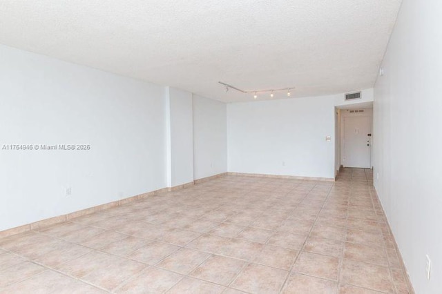 spare room with baseboards, visible vents, a textured ceiling, and track lighting