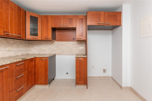 kitchen with light tile patterned flooring, brown cabinets, and light stone countertops