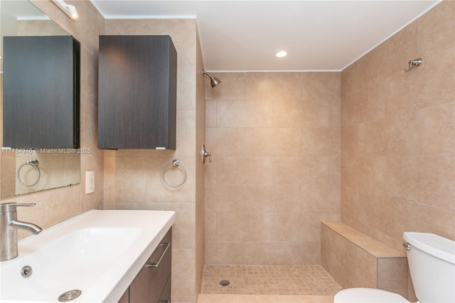 bathroom featuring toilet, vanity, tile walls, and tiled shower