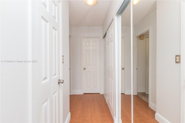 hallway featuring light wood-style floors and baseboards