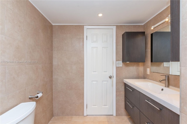 bathroom with toilet, tile patterned floors, tile walls, and vanity