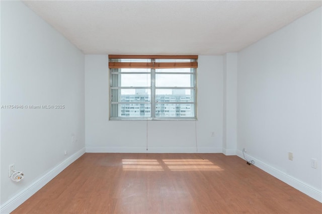 spare room with wood finished floors and baseboards