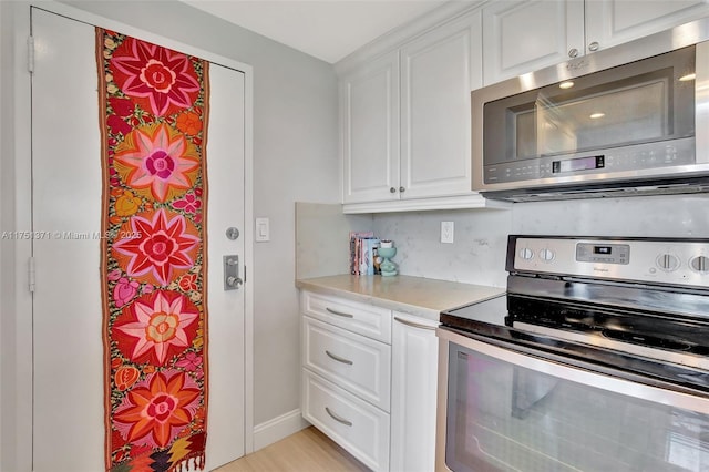 kitchen featuring stainless steel appliances, light countertops, and white cabinetry