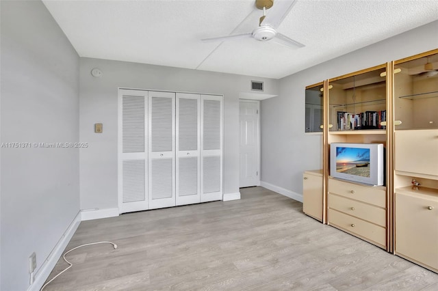 unfurnished bedroom featuring baseboards, a textured ceiling, visible vents, and wood finished floors