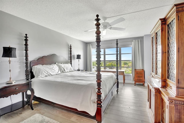 bedroom with light wood-style floors, ceiling fan, a textured ceiling, and baseboards