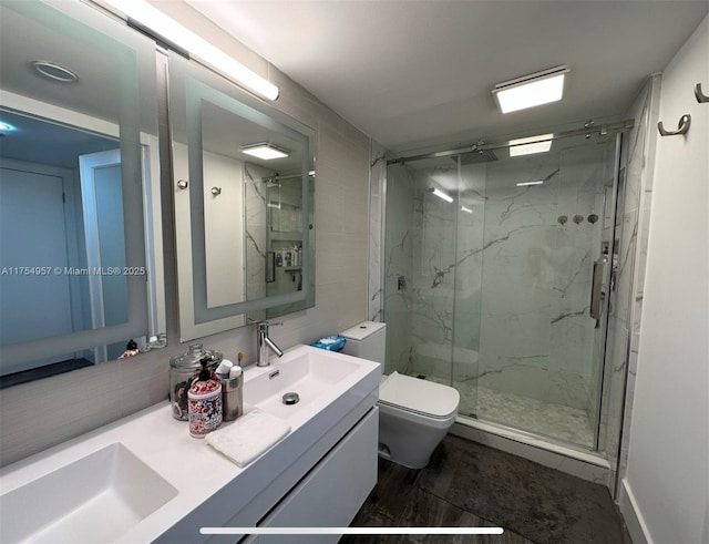 full bathroom featuring a sink, toilet, a marble finish shower, and double vanity