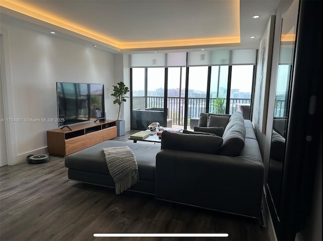 living room featuring recessed lighting, a raised ceiling, wood finished floors, a wall of windows, and baseboards