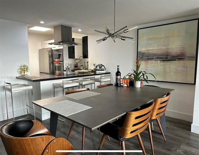 kitchen with island range hood, dark countertops, wood finished floors, a sink, and recessed lighting