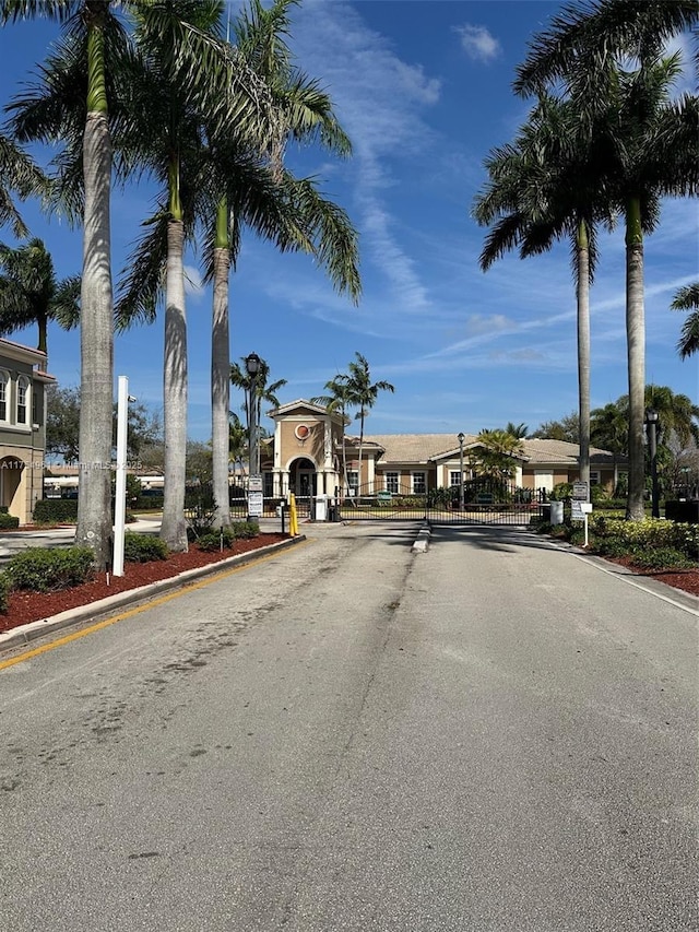 view of road featuring a gate, a gated entry, and curbs