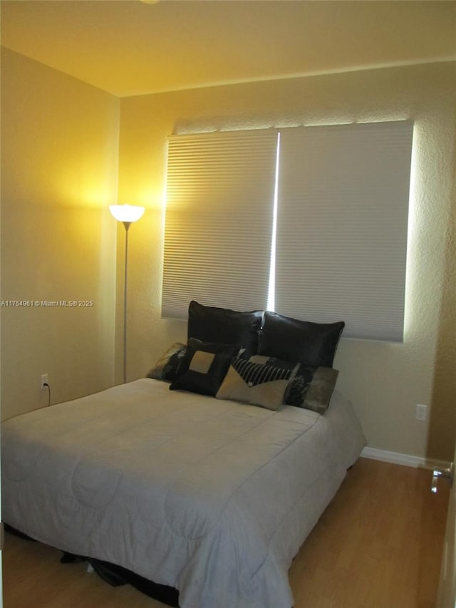 bedroom featuring baseboards and wood finished floors