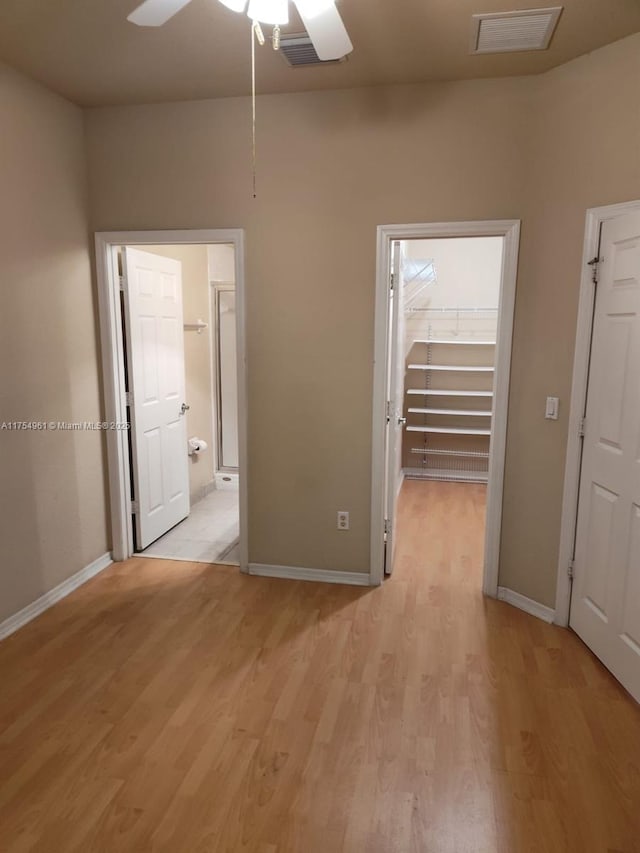 unfurnished room featuring light wood finished floors, baseboards, visible vents, and ceiling fan