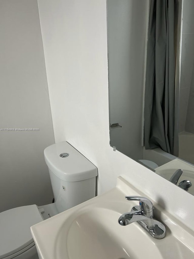 full bathroom with shower / bath combo with shower curtain, a sink, and toilet