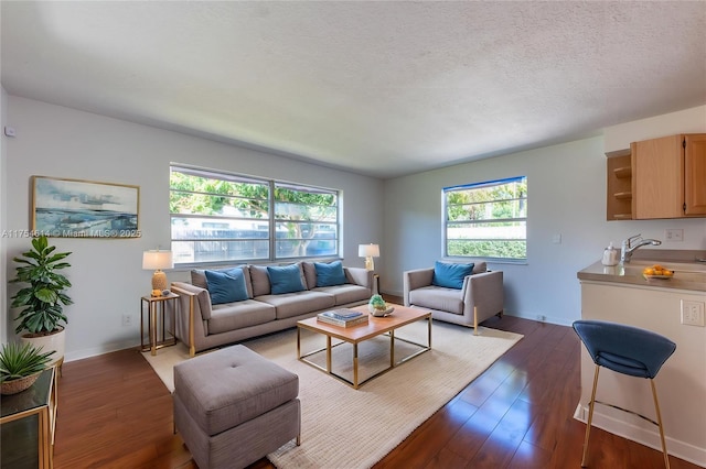living room with dark wood-type flooring, a textured ceiling, and baseboards