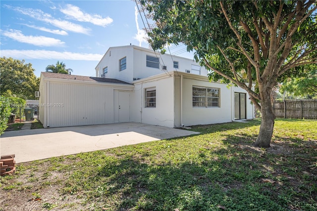 rear view of property with a yard, stucco siding, fence, and a patio